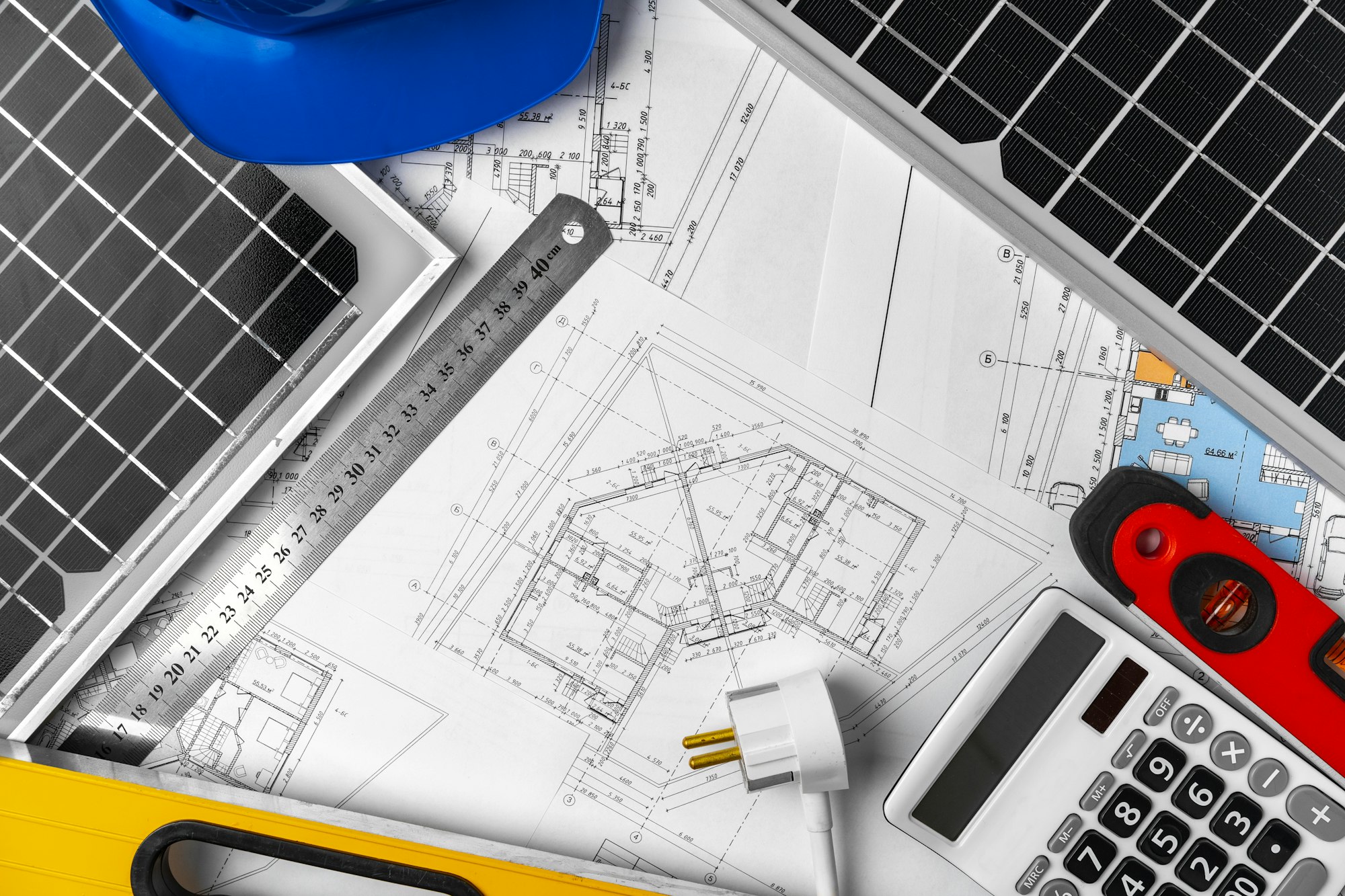 Construction blueprints, hardhat and solar battery on architect's table