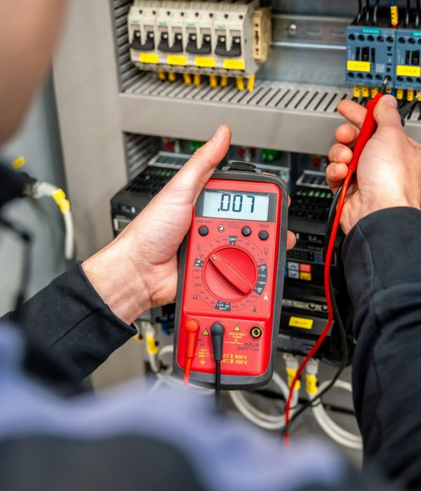 Worker measuring and repairing an electrical system panel